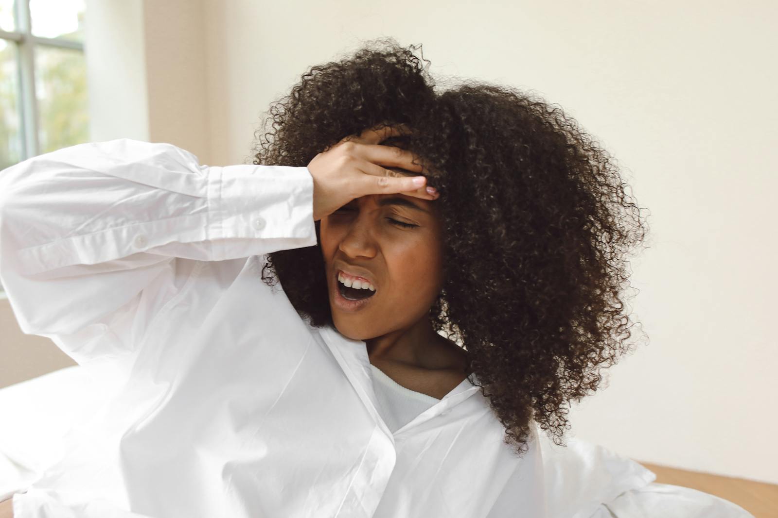 Close-Up Shot of a Curly-Haired Woman in White Long Sleeves